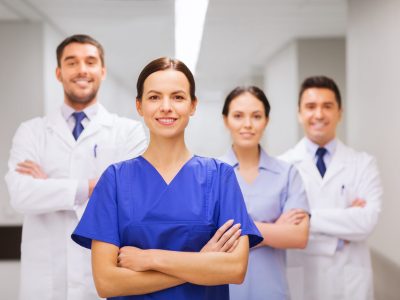 clinic, profession, people, health care and medicine concept - happy group of medics or doctors at hospital corridor