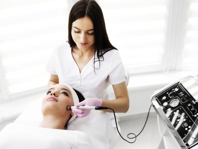 A woman came to laser hair removal facial. The woman lies and smiles, the doctor leads him in the face with a modern laser epilator. They are in the modern clinic.close up